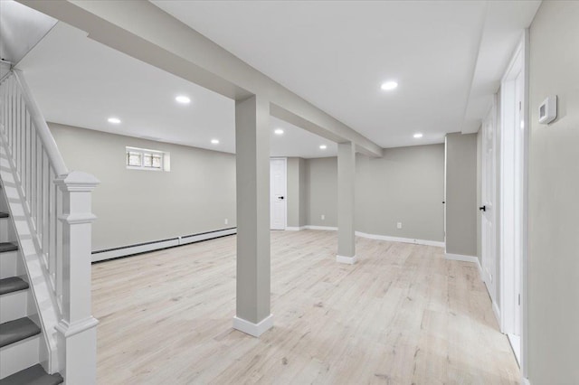 basement with light wood-style floors, recessed lighting, a baseboard heating unit, and stairway