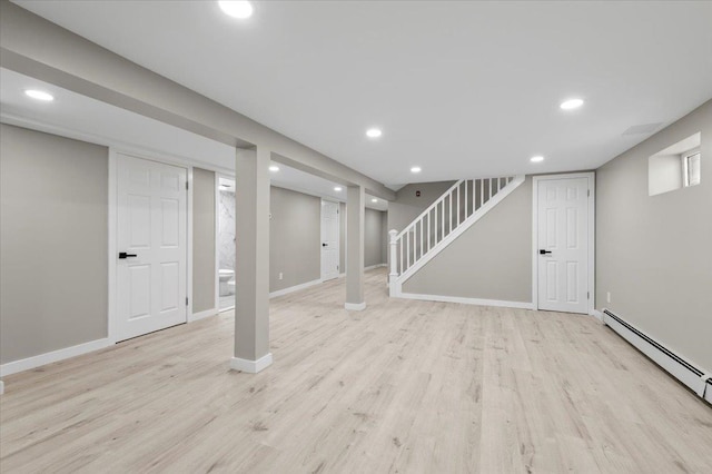 finished below grade area featuring baseboard heating, light wood-type flooring, stairway, baseboards, and recessed lighting