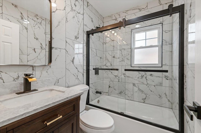 bathroom featuring vanity, toilet, shower / bath combination with glass door, and tile walls
