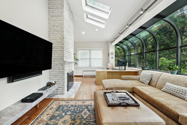 5235 Netherland Ave, Bronx, NY 10471 - living room with radiator, a skylight, wood finished floors, a fireplace, and lofted ceiling