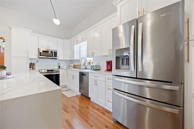 kitchen with appliances with stainless steel finishes, a sink, and white cabinetry