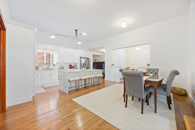 dining space with baseboards and light wood finished floors