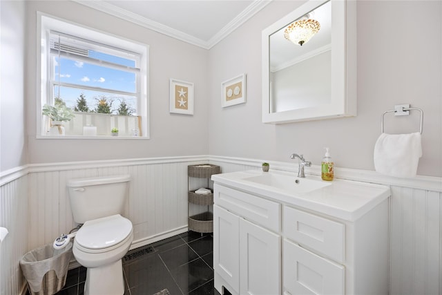 half bathroom with wainscoting, toilet, vanity, and tile patterned flooring