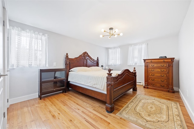 bedroom with baseboard heating, baseboards, an inviting chandelier, and light wood-style flooring