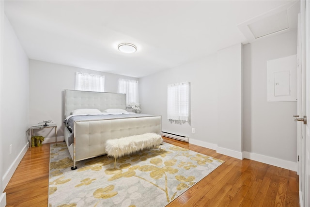 bedroom featuring attic access, baseboards, wood finished floors, and electric panel