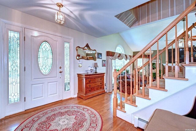 150 N Woods Dr, Wading River, NY 11792 - entrance foyer featuring stairs, lofted ceiling, a baseboard radiator, and wood finished floors