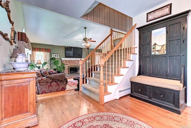 150 N Woods Dr, Wading River, NY 11792 - entrance foyer featuring light wood-style floors, a baseboard heating unit, a brick fireplace, and stairway