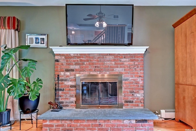 150 N Woods Dr, Wading River, NY 11792 - details with a baseboard radiator, a brick fireplace, ceiling fan, and wood finished floors