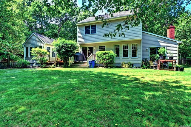 150 N Woods Dr, Wading River, NY 11792 - rear view of house with a wooden deck, fence, and a lawn