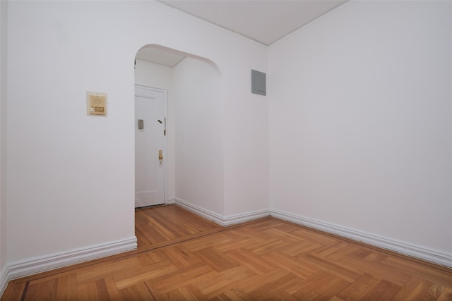 empty room with baseboards, arched walkways, and ornamental molding