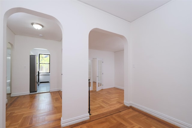 hall with baseboards, ornamental molding, and arched walkways