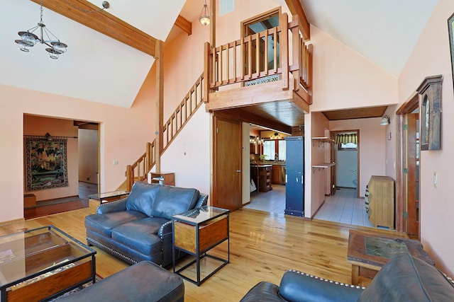 living area featuring stairway, high vaulted ceiling, hardwood / wood-style flooring, and an inviting chandelier