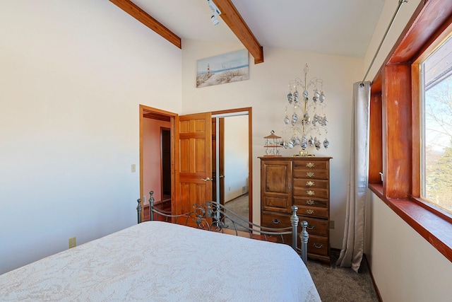 bedroom featuring lofted ceiling with beams, dark colored carpet, and multiple windows