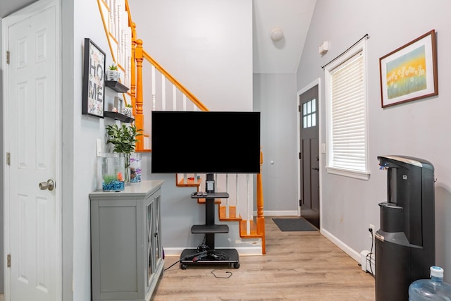 entrance foyer featuring light wood-style floors, baseboards, lofted ceiling, and stairway
