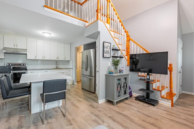 kitchen with light countertops, appliances with stainless steel finishes, under cabinet range hood, and light wood-type flooring