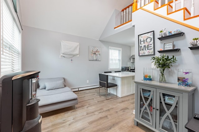 office space featuring light wood-style floors, a baseboard heating unit, and high vaulted ceiling