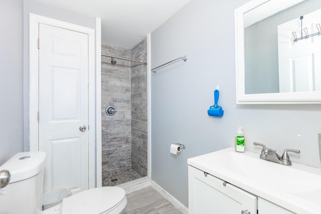 full bathroom featuring toilet, baseboards, a shower stall, and vanity