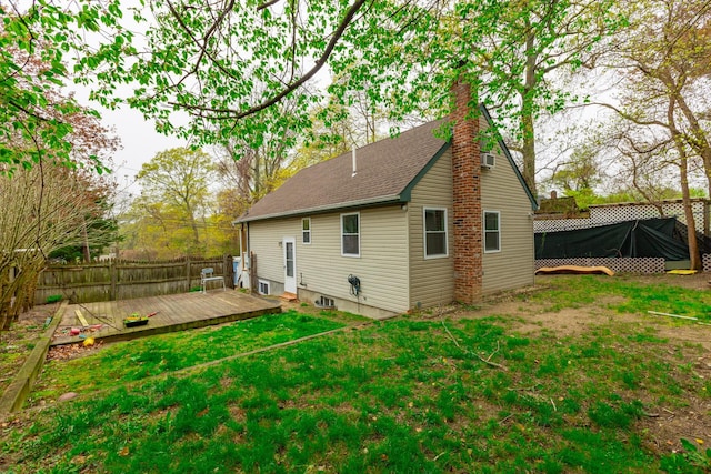 back of house featuring a lawn, a wooden deck, fence, and a chimney