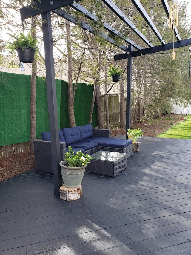 wooden terrace with an outdoor hangout area, fence, and a pergola