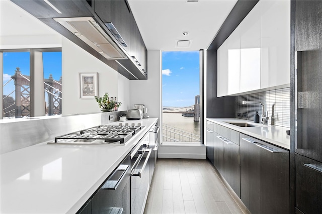 kitchen featuring white cabinetry, a sink, appliances with stainless steel finishes, light countertops, and modern cabinets