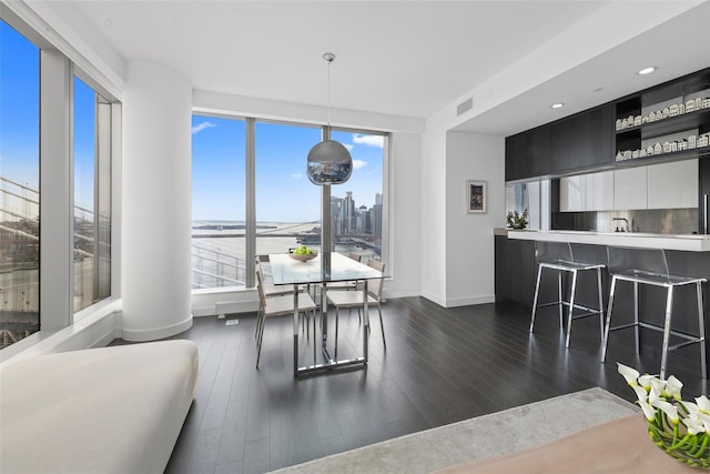living room featuring dark wood-style flooring, visible vents, a healthy amount of sunlight, and baseboards