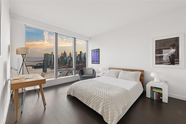 bedroom featuring a wall of windows, wood finished floors, and baseboards