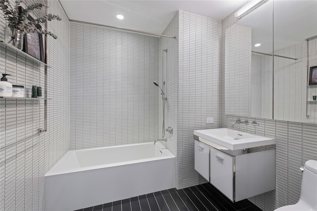 full bathroom with tile walls, washtub / shower combination, toilet, and vanity