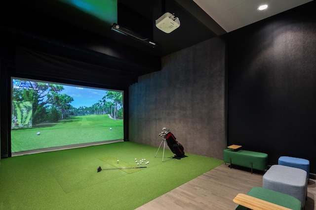 game room with wood finished floors and golf simulator
