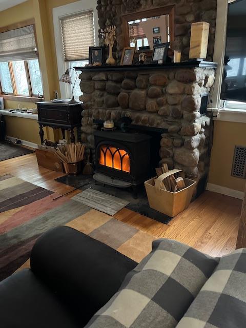 interior details featuring wood finished floors, a wood stove, baseboards, and visible vents