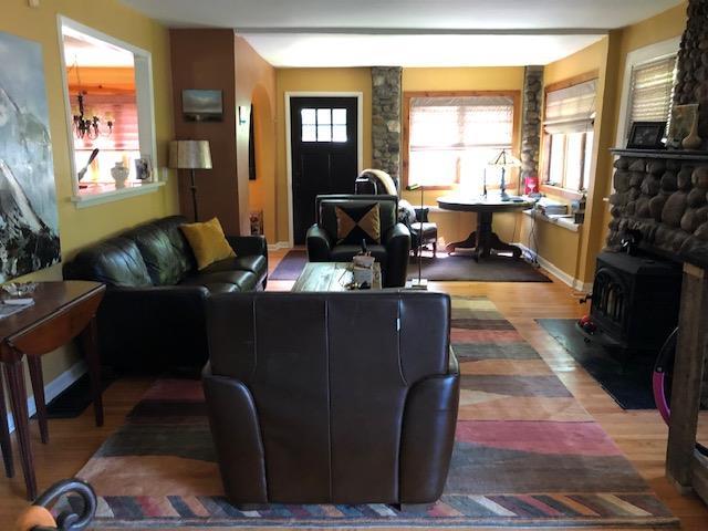 living area featuring baseboards, wood finished floors, and a wood stove