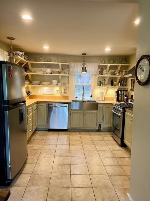 kitchen with recessed lighting, stainless steel appliances, open shelves, light tile patterned floors, and a sink
