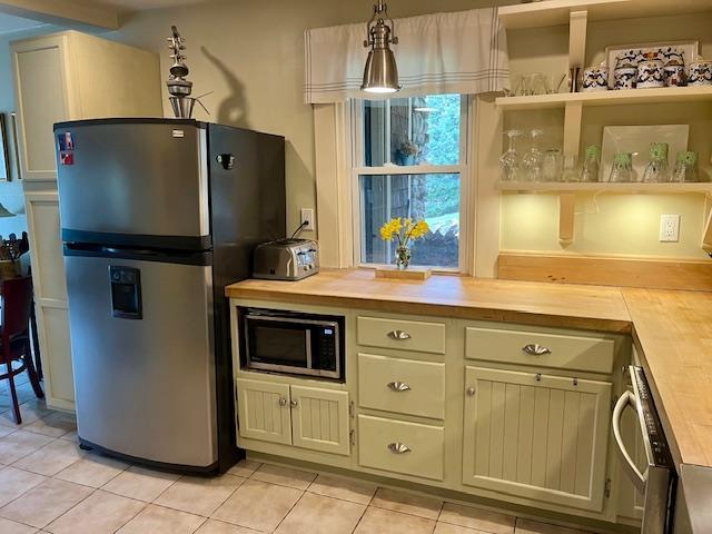 kitchen featuring open shelves, light tile patterned floors, wooden counters, and appliances with stainless steel finishes