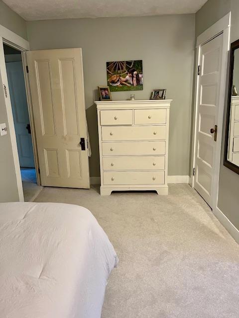 bedroom with light carpet and baseboards