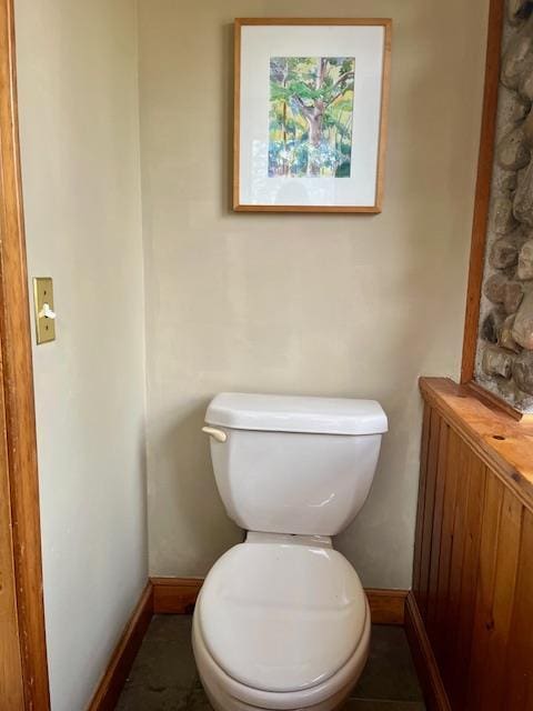 half bath featuring baseboards and toilet