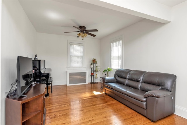 living area featuring light wood-type flooring, a ceiling fan, and baseboards
