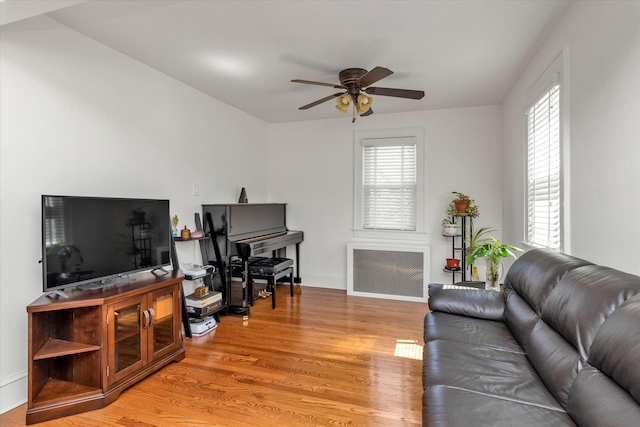living room featuring radiator, ceiling fan, light wood-type flooring, and a wealth of natural light