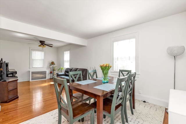 dining area with baseboards, a ceiling fan, and light wood-style flooring