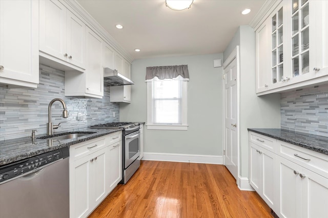 kitchen featuring white cabinets, a sink, stainless steel appliances, under cabinet range hood, and glass insert cabinets
