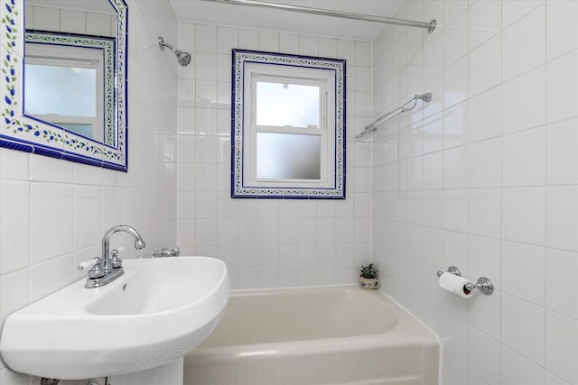 bathroom featuring a sink, tile walls, and bathtub / shower combination