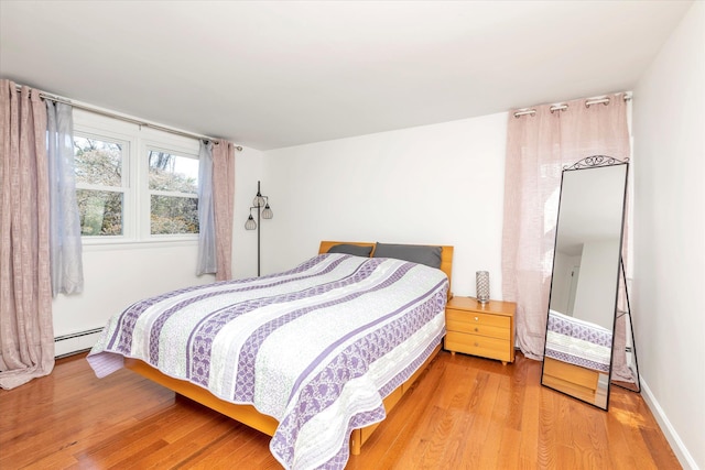 bedroom with light wood-style flooring and a baseboard heating unit