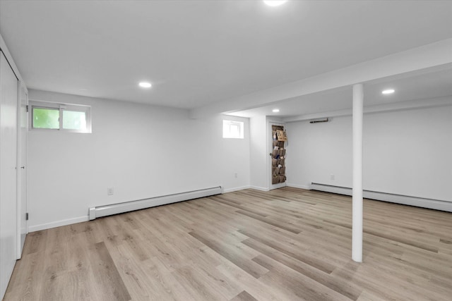 below grade area with a healthy amount of sunlight, light wood finished floors, a baseboard heating unit, and recessed lighting