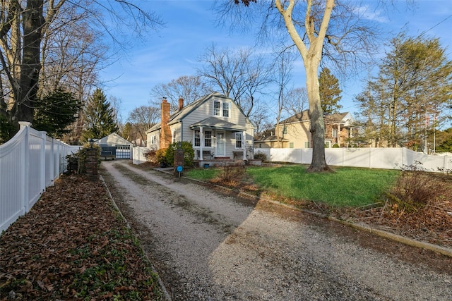 view of front of house with a front yard, fence private yard, an outbuilding, and a chimney
