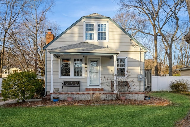 view of front of home with a chimney, fence, roof with shingles, and a front yard