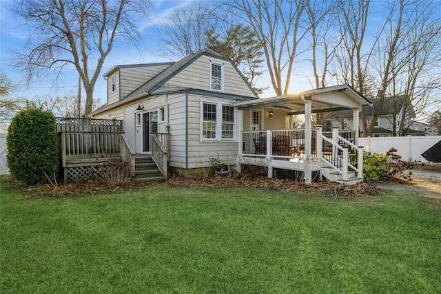 rear view of property with a lawn, fence, a deck, and covered porch