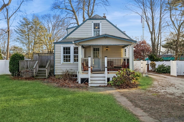bungalow-style house featuring fence, a front lawn, covered porch, and a chimney