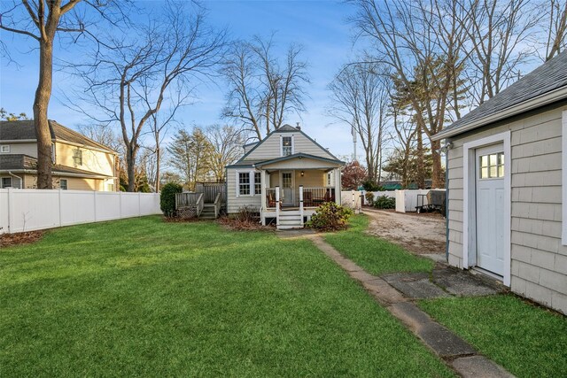 back of house with fence, a lawn, and a deck