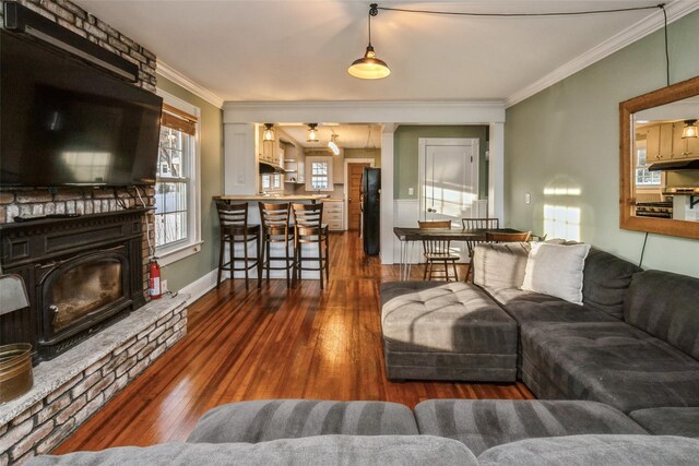 living area with baseboards, ornamental molding, and wood-type flooring