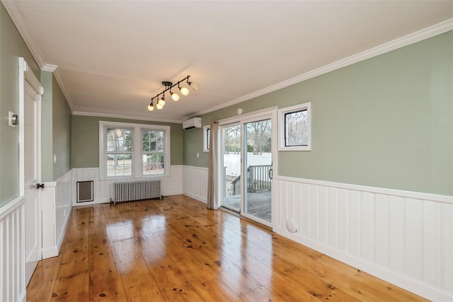 unfurnished room featuring a wainscoted wall, light wood finished floors, radiator, ornamental molding, and a wall unit AC
