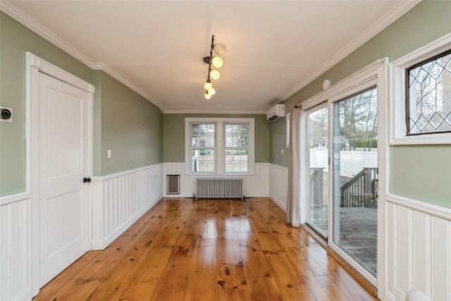 unfurnished dining area featuring radiator, plenty of natural light, a wainscoted wall, and a wall unit AC