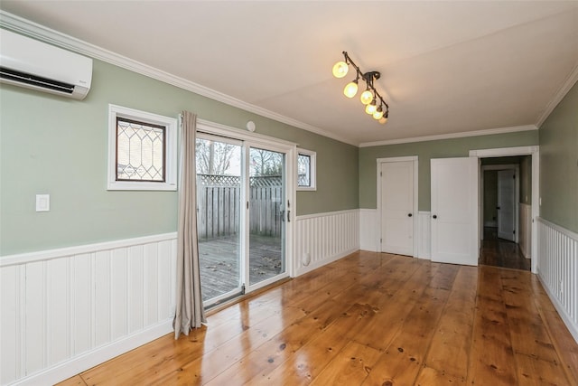 unfurnished dining area with light wood-style flooring, an AC wall unit, ornamental molding, and wainscoting